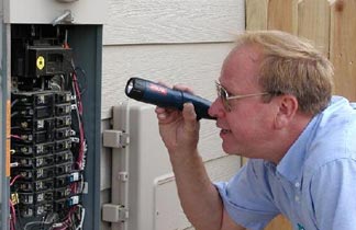 man in blue shirt inspecting a circuit breaker